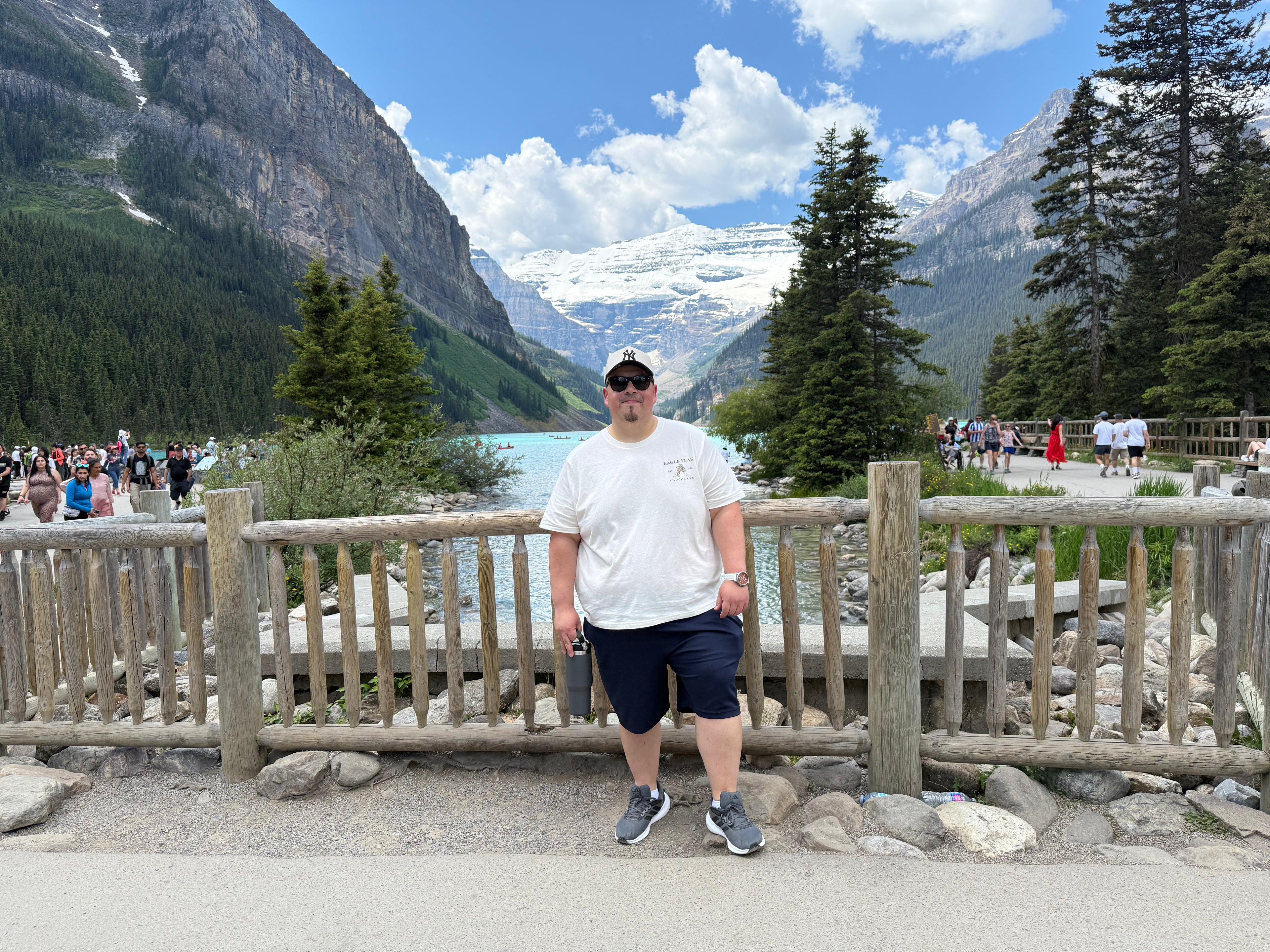 Grace Over All™ founder Marcelo Ortiz standing at Lake Louise in Banff National Park, Alberta, with mountains, evergreen trees, and the lake in the background.