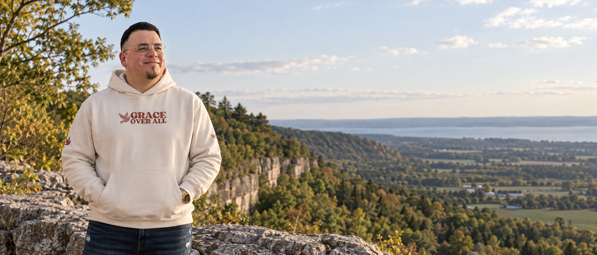 Grace Over All founder wearing the Signature Dove hoodie at an Ontario escarpment overlook with a natural Canadian landscape in the background.