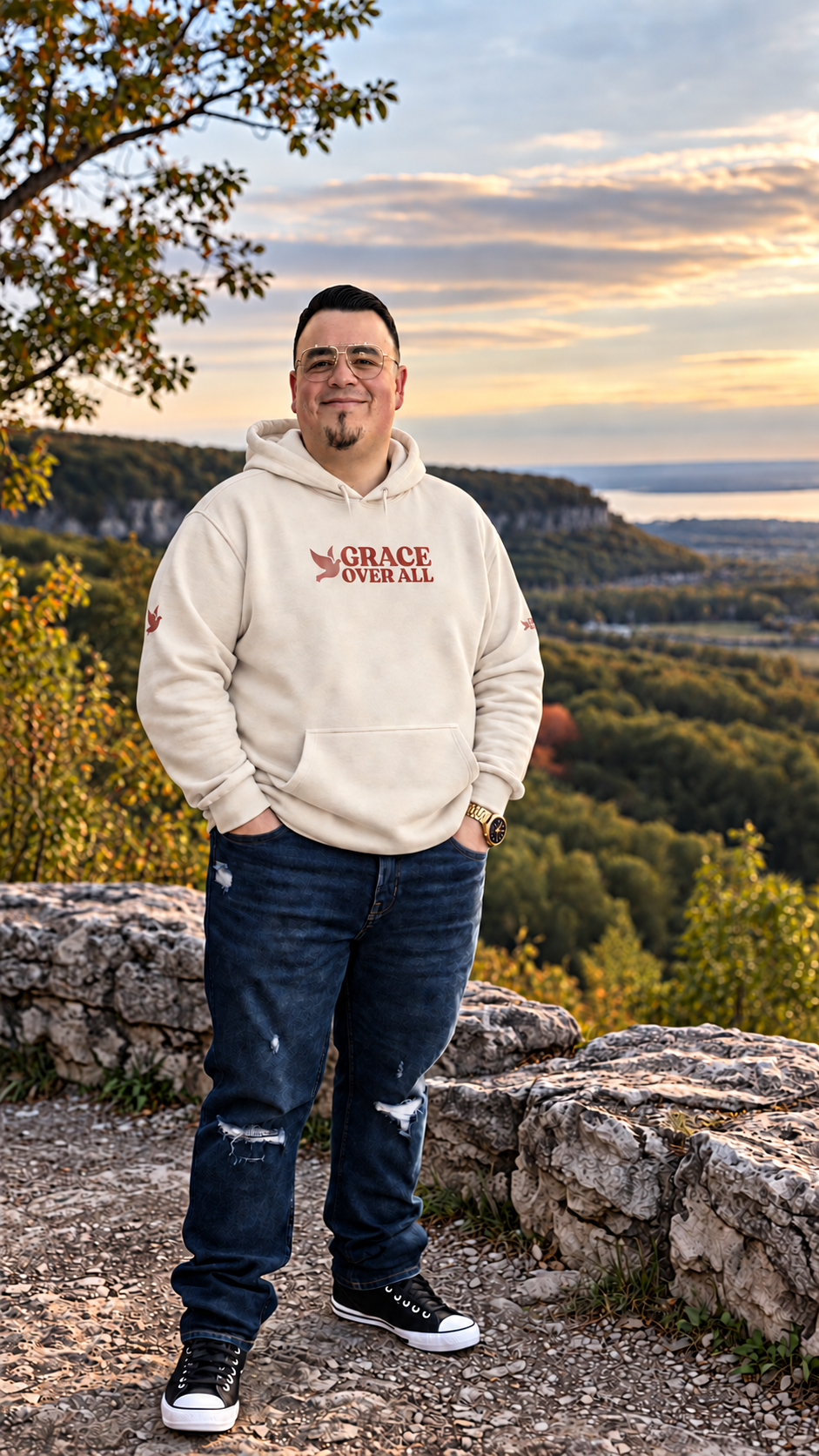 Grace Over All founder wearing the cream Signature Dove hoodie at an Ontario escarpment overlook surrounded by a natural Canadian landscape.