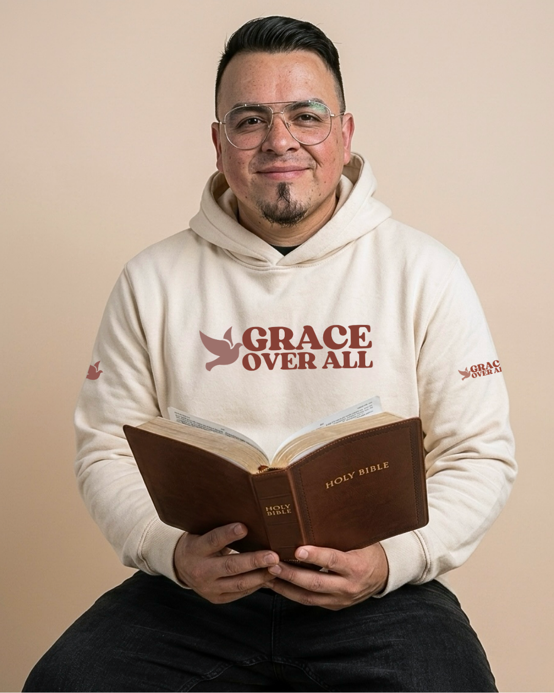 Man wearing Grace Over All hoodie while reading the Holy Bible, representing faith, purpose, and everyday devotion.